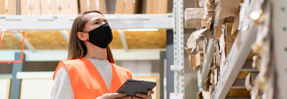 A female wearing a black mask, a hazard jacket while maintaining the inventory