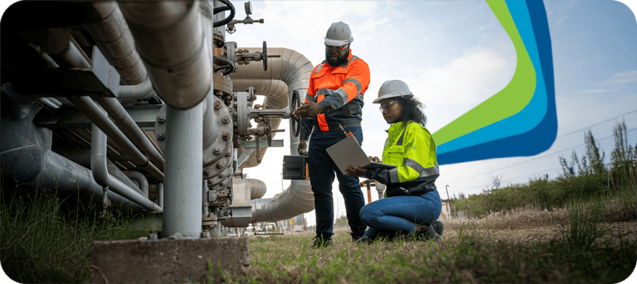 Two industrial workers inspecting pipeline equipment outdoors