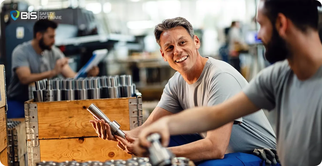 Factory workers inspecting metal parts in an industrial workshop.
